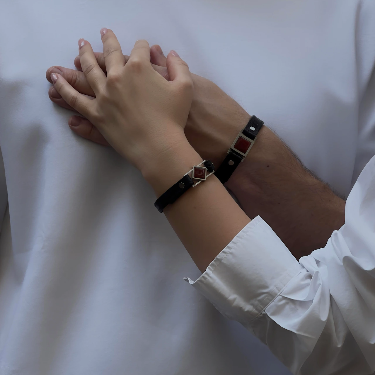 Matching Core & Path bracelets with red agate inserts worn by a couple, symbolizing passion and connection